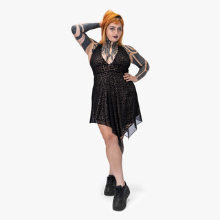 Woman wearing a black lace dress with tattoos on arms and legs against a white background